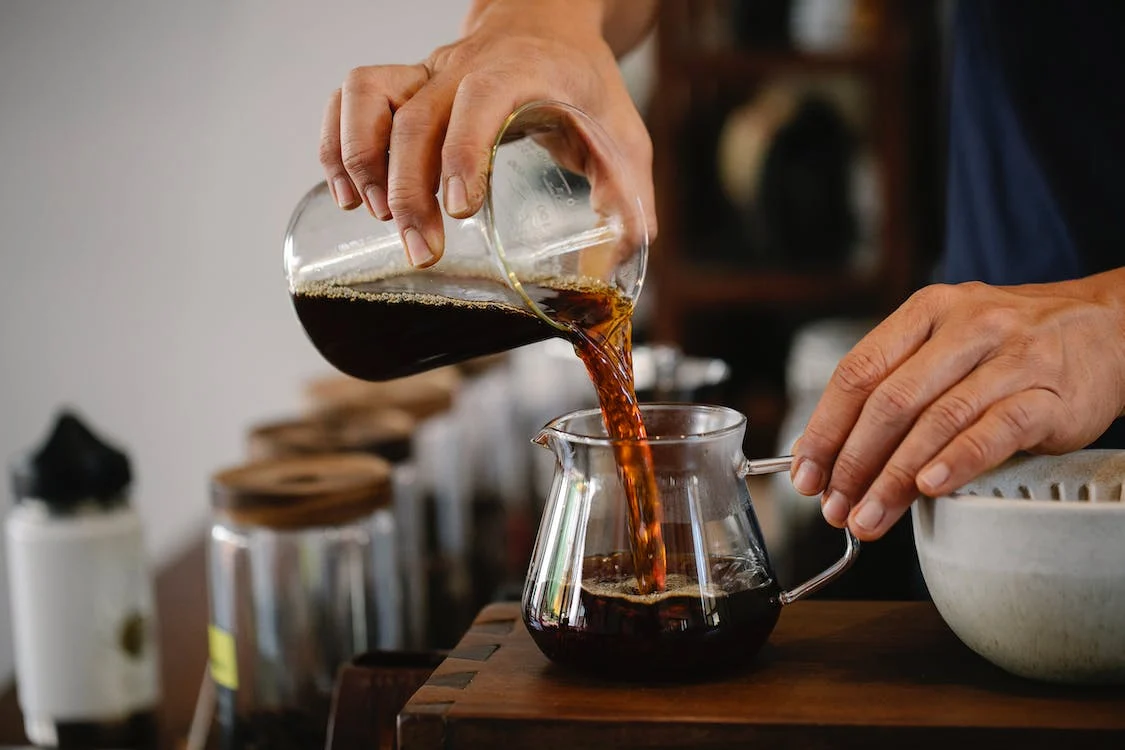 close-up of brewed coffee from glass pot being poured into glass