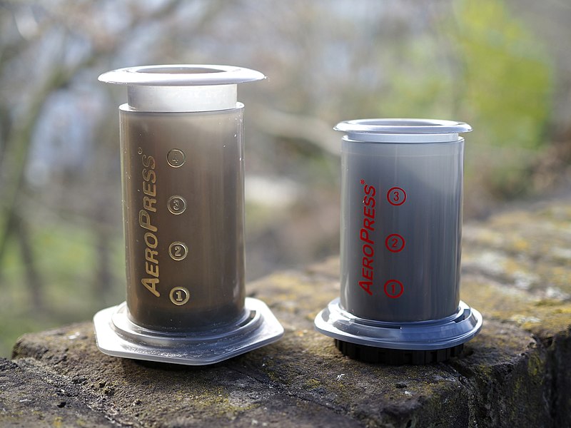 An Aeropress manual coffee maker next to a smaller Aeropress Go
