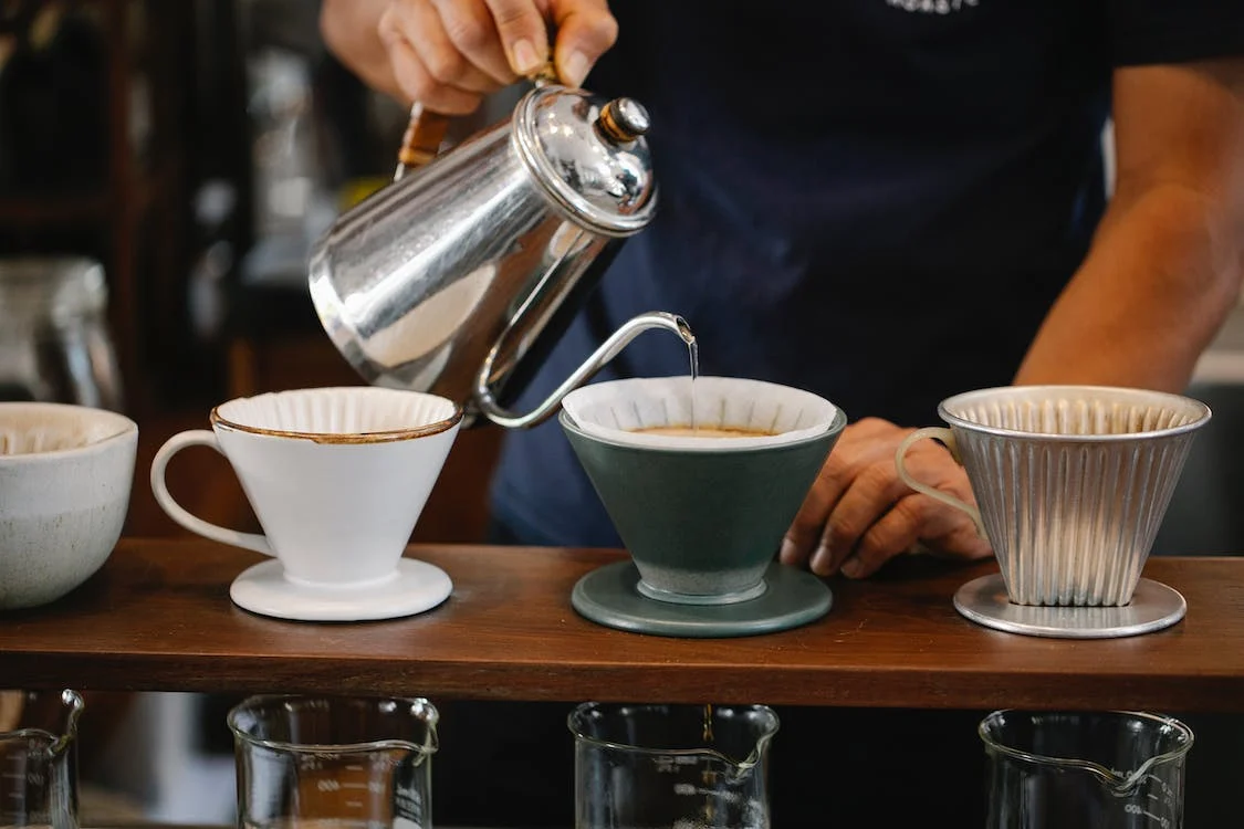 barista pouring water into each coffee dilter