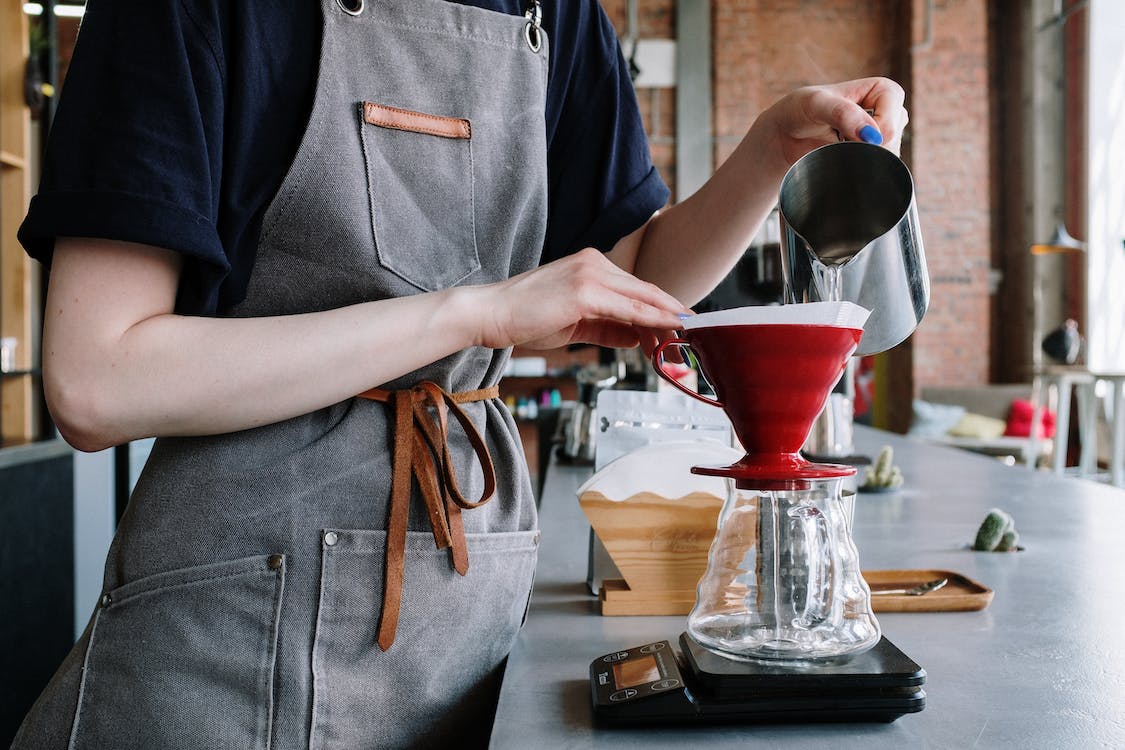 A person pouring water on coffee dripper with a coffee scale on the bottom