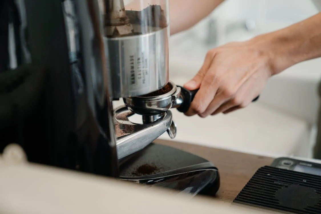 Person tamping ground espresso into a portafilter
