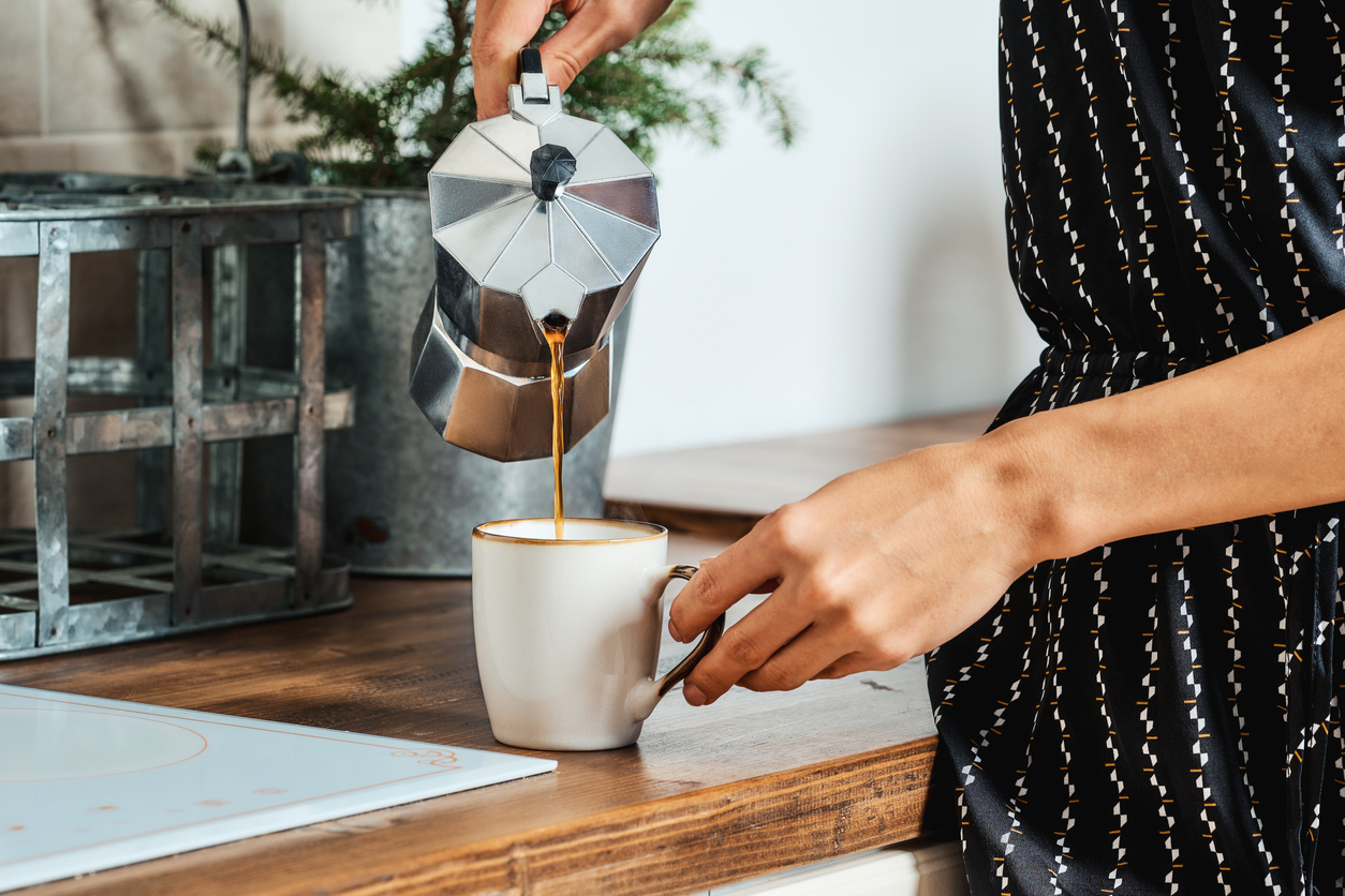 female hand pouring coffee from the geyser coffee maker into cup
