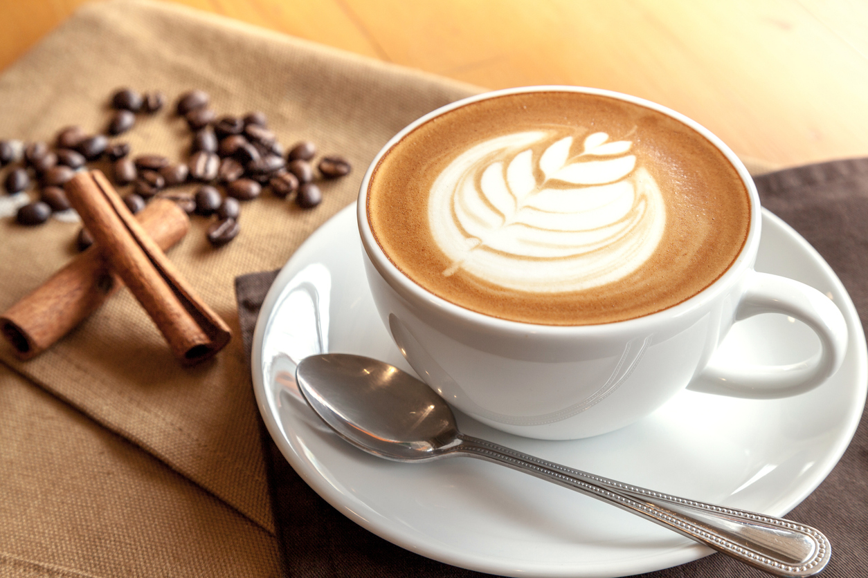 Cup of café latte with coffee beans and cinnamon sticks