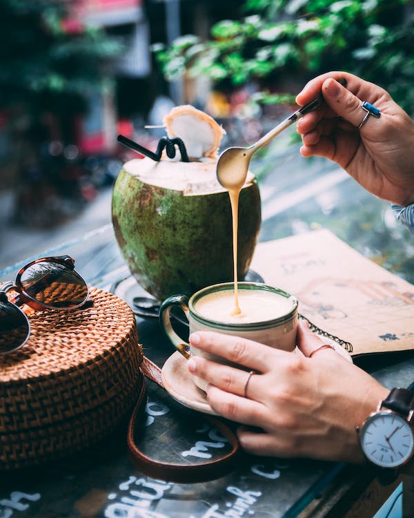 cup of coffee with opened young coconut at the side