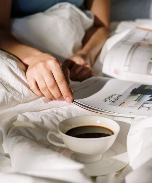 a cup of coffee kept on a white bed.