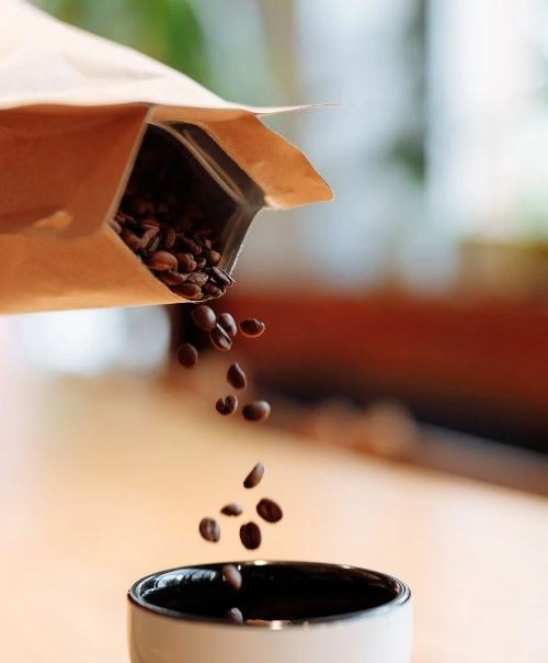Person pouring coffee beans in a jar