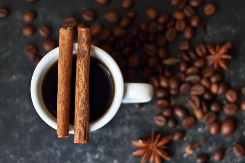 a cup of coffee with two cinnamon sticks on top