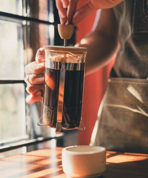 A person making coffee in a French press