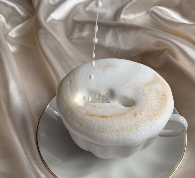 Pouring milk in a cup of coffee on a bed 