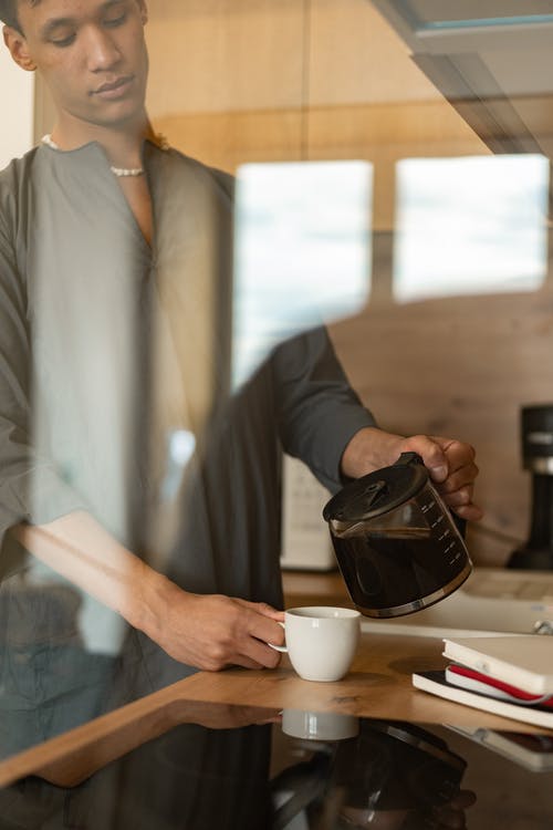 a person pouring cold coffee into a mug.
