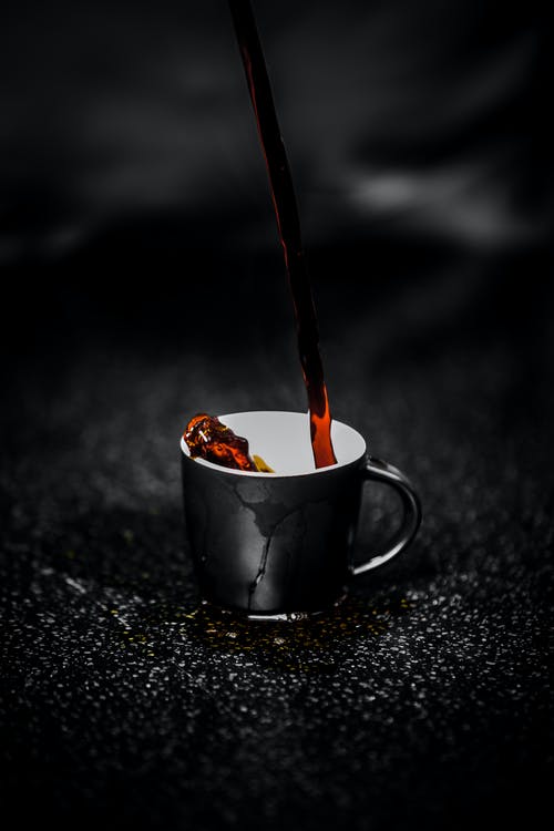 strong coffee being poured into a black cup.