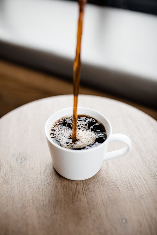 white mug with coffee pouring.
