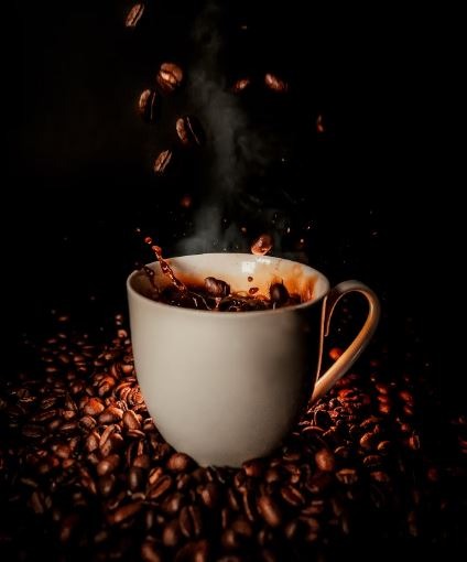 cup of steaming coffee on roasted beans