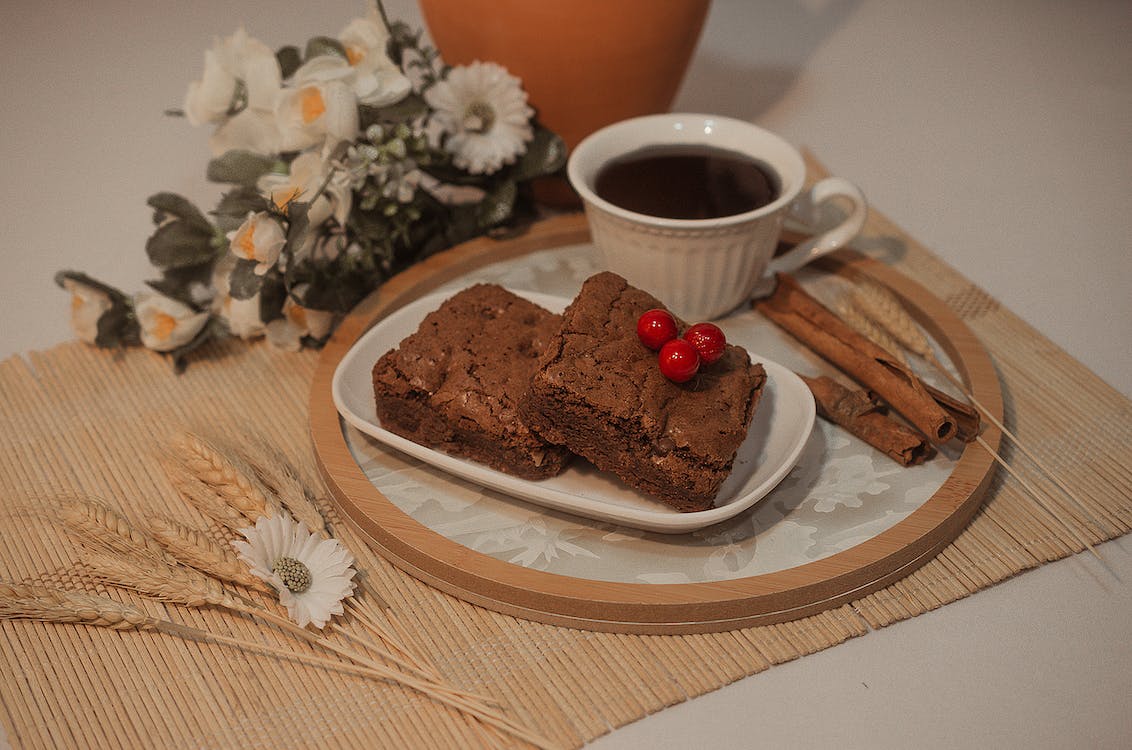 A cup of coffee and a plate of chocolate brownies on the table