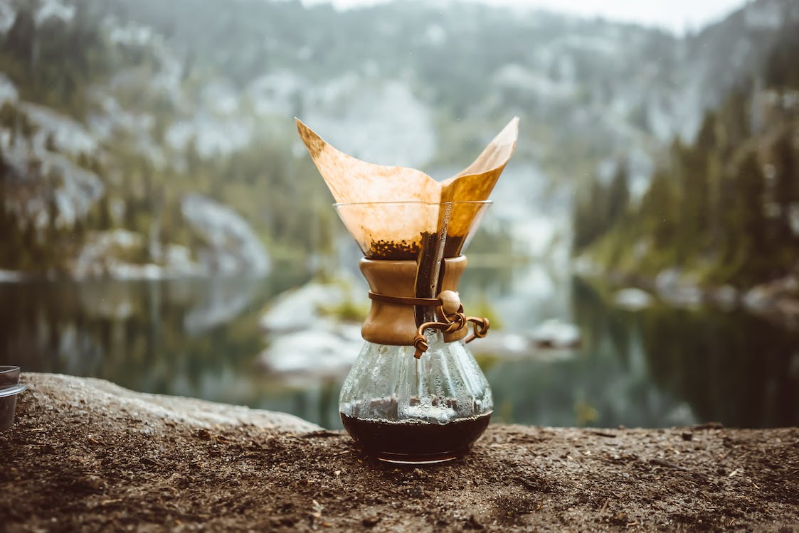 A pour-over coffee maker on a rock in a mountains