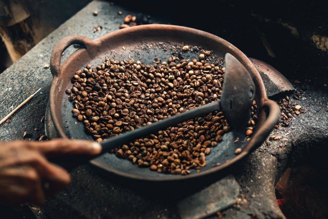 Coffee beans being roasted on a round wok